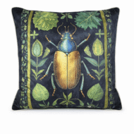 Black scatter cushion featuring a luminous gold and blue scarab beetle framed by green botanical leaves