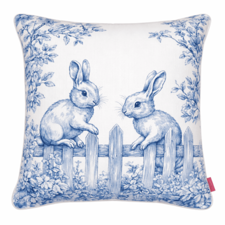 Blue and white toile-style scatter cushion featuring two illustrated bunnies perched on a garden fence