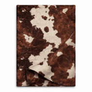 Cowhide print table runner in deep brown and ivory tones, folded to show fabric texture