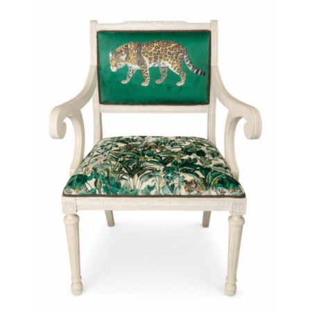 White carved armchair with green leopard print backrest and jungle print seat.