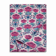 Ivory table runner with bold pink floral print and teal botanical stems, folded to show fabric texture