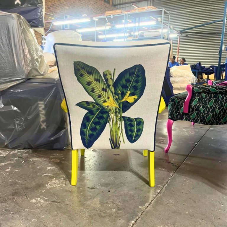 Yellow-legged chair with botanical leaf print backrest, rear view.