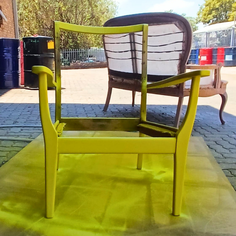 Freshly painted yellow chair frame drying outdoors before upholstery.